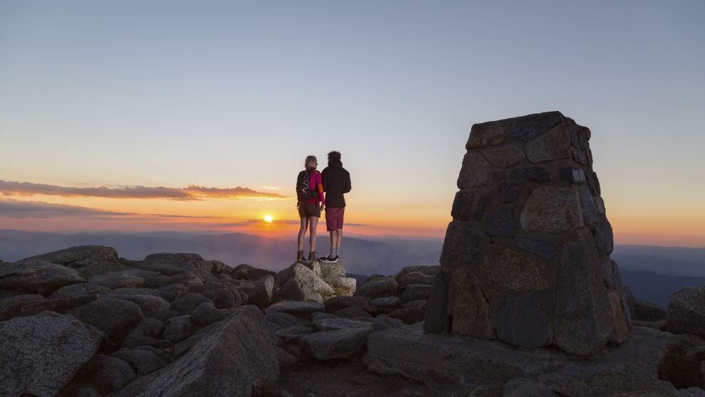 Couple watching the sun set at the summit of Mount Kosciuszko in Kosciuszko National Park