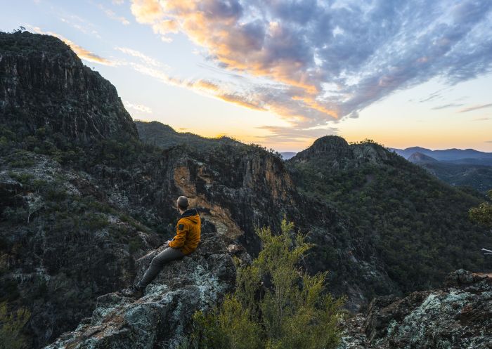 Hiker watching sunset over volcanic rock formations, Warrumbungle National Park