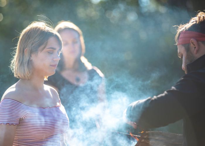 Aboriginal guide Dwayne Bannon-Harrison performing a smoking ceremony during a traditional welcome on a Ngaran Ngaran Culture Awareness tour