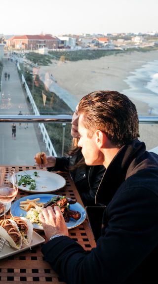 Friends enjoying food and drink with ocean views at Merewether Surfhouse, Newcastle