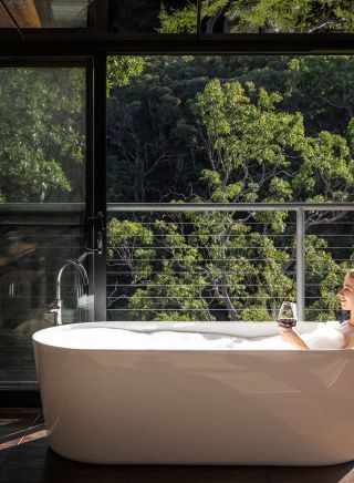 Woman relaxing in the bath with views at Spicers Sangoma Retreat, Bowen Mountain