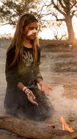 Young girl from the Barkindji nation preparing leaves for a smoking ceremony, Wilcannia