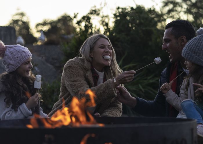 Family relaxing and roasting marshmallows at their waterfront campsite, Cockatoo Island
